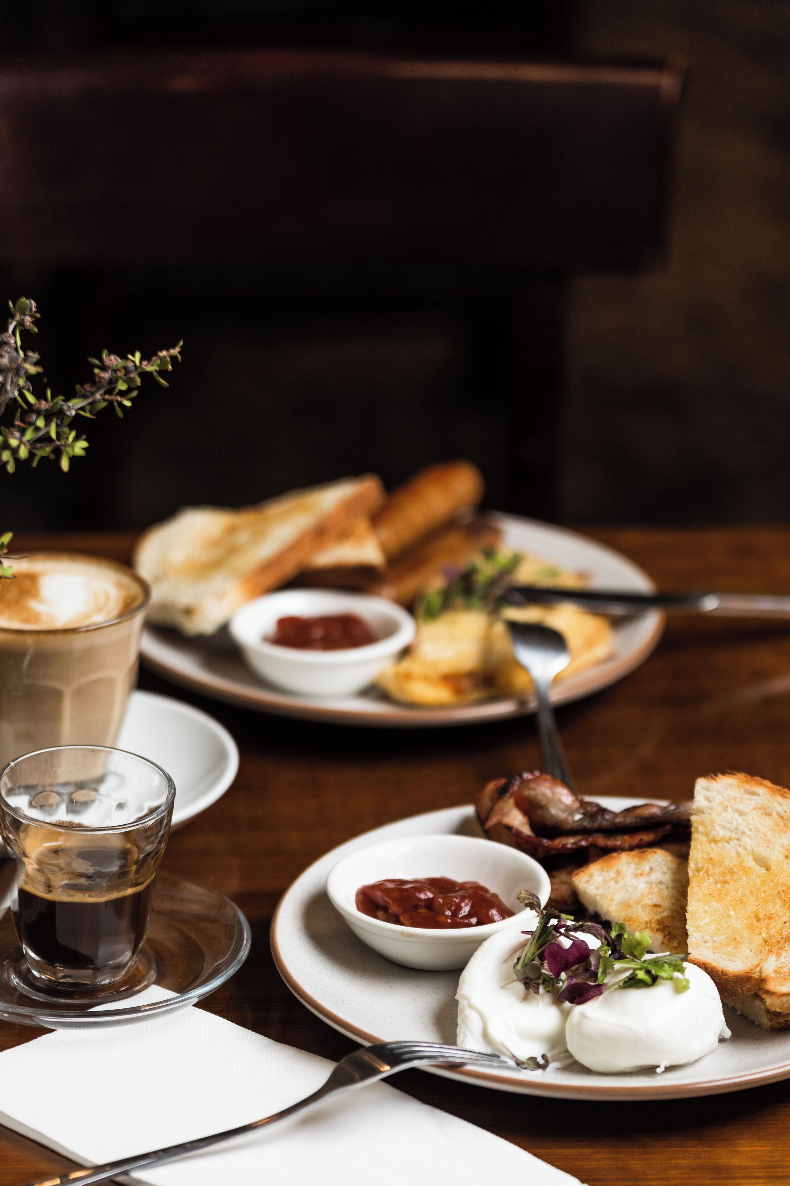 Un desayuno con tostadas, huevos y café sobre una mesa de madera.