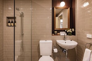 A bathroom with a glass-enclosed shower, a white toilet, and a sink with a mirror above it. - Hadley's Orient Hotel (Hobart)