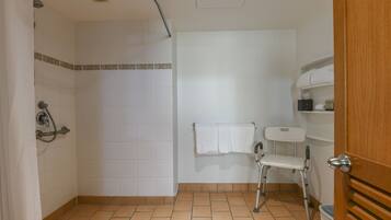 A bathroom with a shower, a toilet, a sink, and a wheelchair-accessible bench.