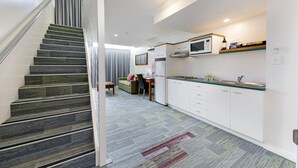 Una cocina moderna con armarios blancos, un microondas y un comedor con mesa y sillas.
