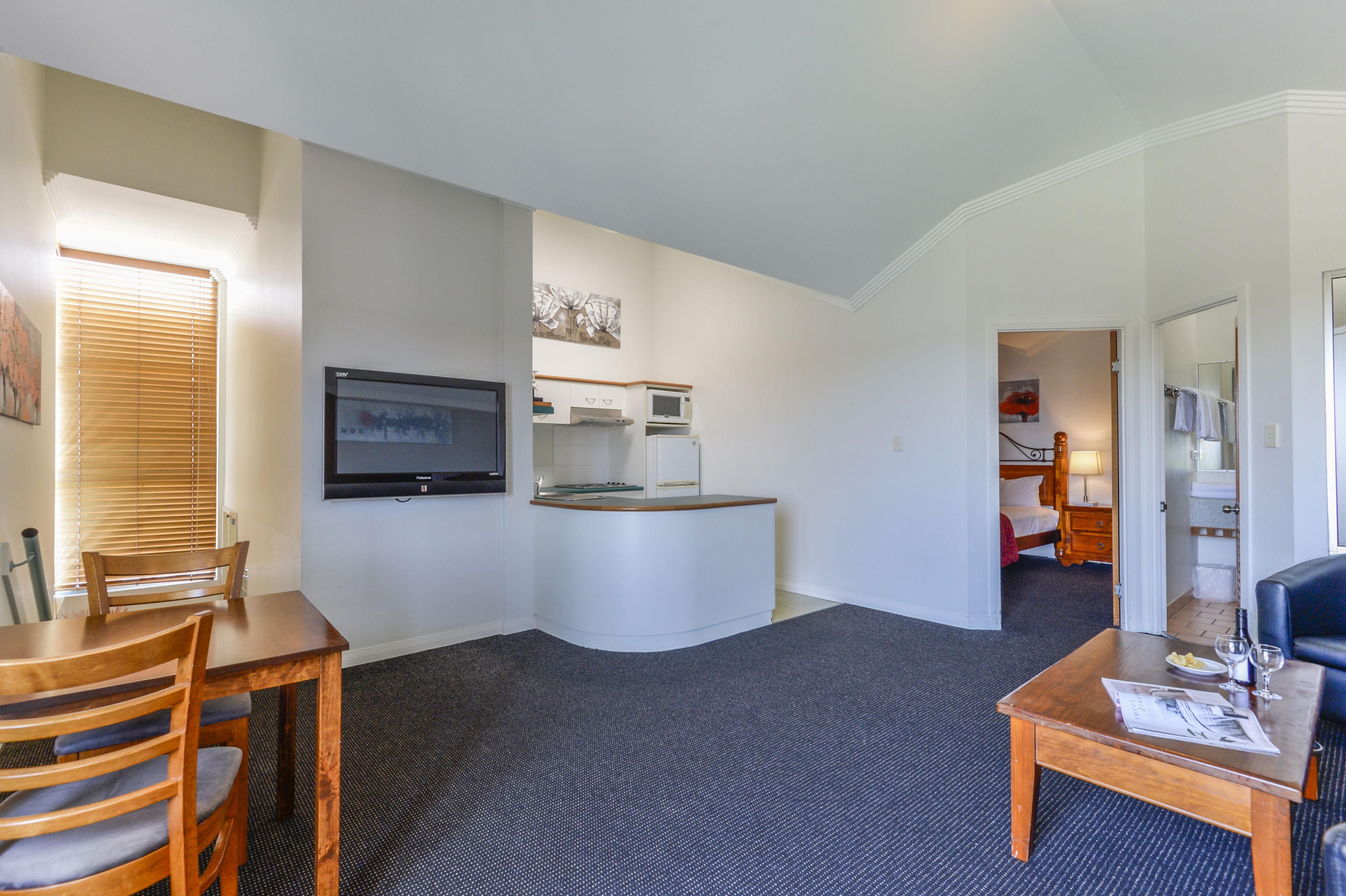 A hotel room with a dining area, kitchenette, and a separate bedroom.