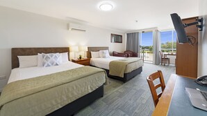 Habitación de hotel con dos camas, un escritorio con una computadora portátil, una silla, un televisor y un balcón con vistas.