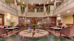 A spacious lobby with a central round table, seating arrangements, and decorative plants. - Quality Hotel D V Manor (Vijayawada)