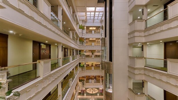 A multi-level hotel atrium with a central open space, balconies, and a grand staircase. - Quality Hotel D V Manor (Vijayawada)