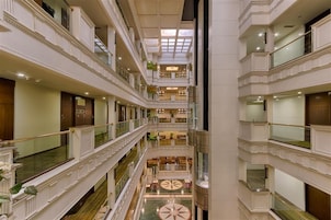 Ein mehrgeschossiges Hotel-Atrium mit einem zentralen Innenhof, Balkonen und einer imposanten Treppe.