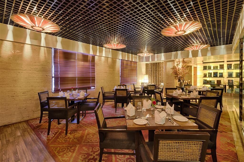 A dining area with tables set for service, a patterned carpet, and a ceiling with a grid design.
