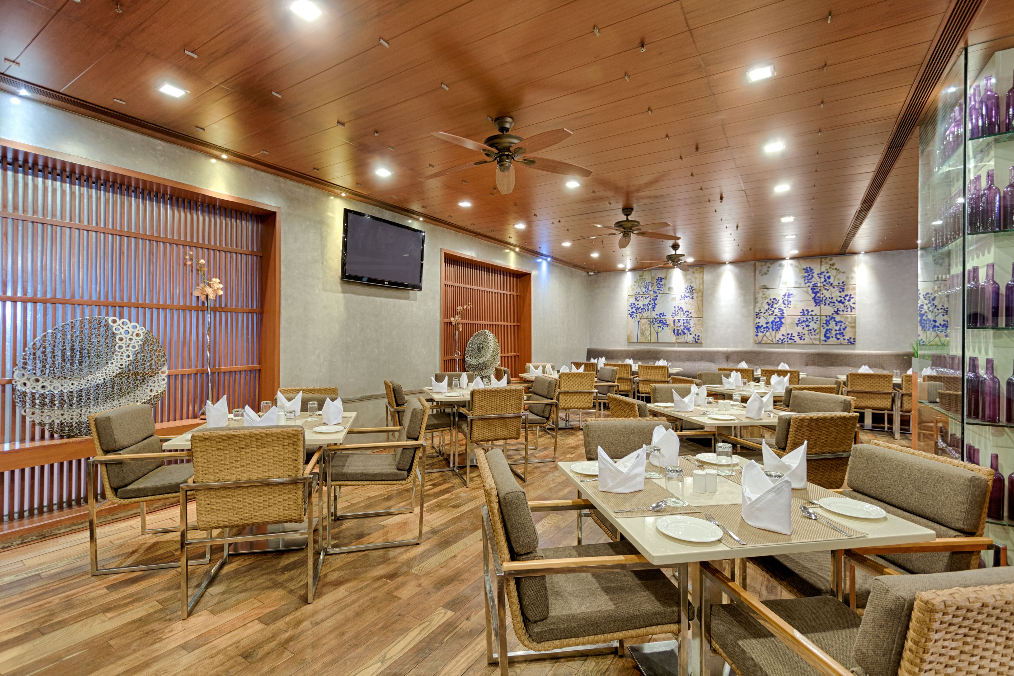 A restaurant with wooden floors, wicker chairs, and tables set for dining.