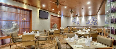 Un restaurante con suelos de madera, sillas de mimbre y mesas dispuestas para comer.