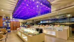A modern hotel lobby with a central buffet area, a reception desk, and a decorative ceiling. - Quality Hotel D V Manor (Vijayawada)
