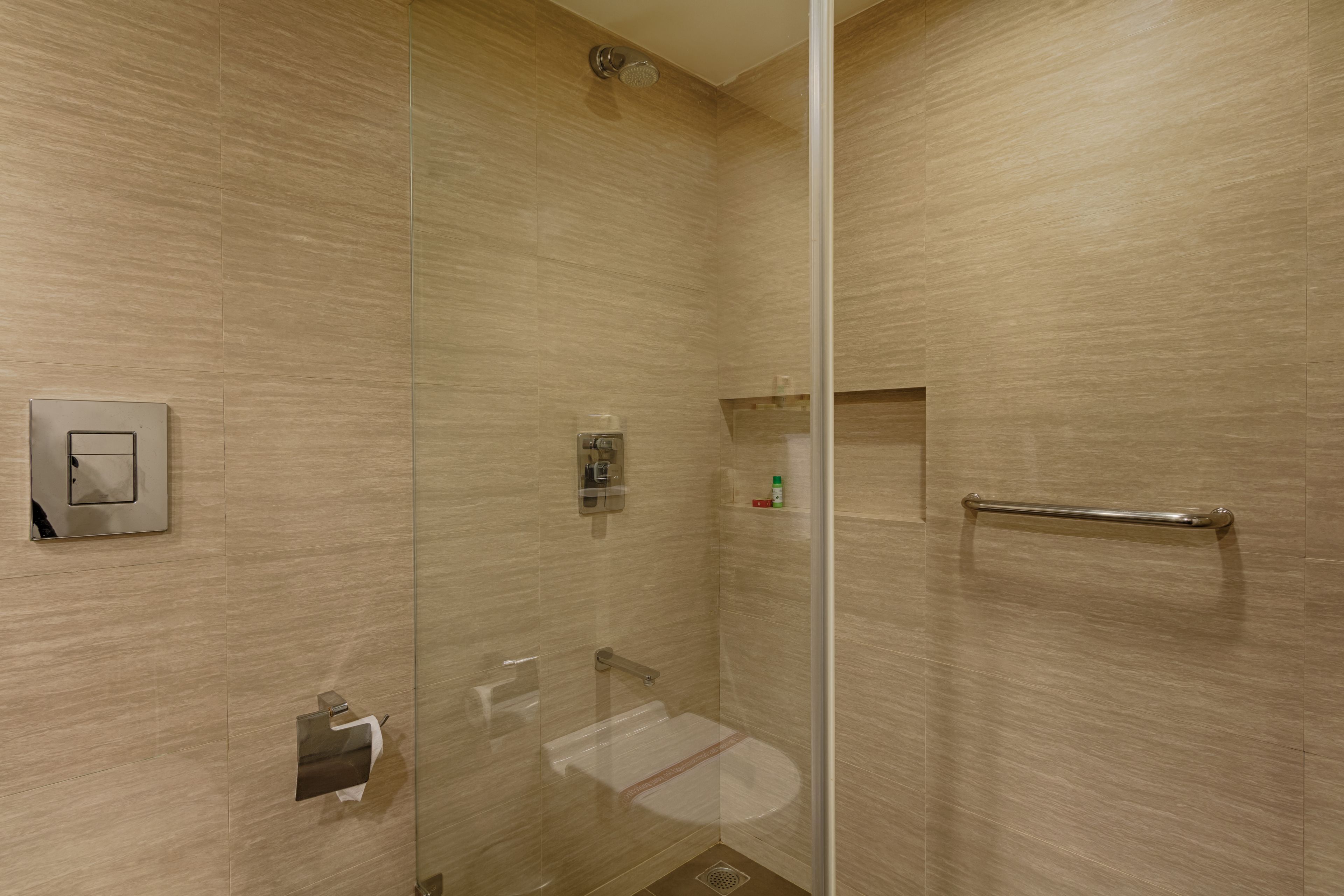 A modern bathroom with a glass-enclosed shower, a towel dispenser, and a hand dryer.