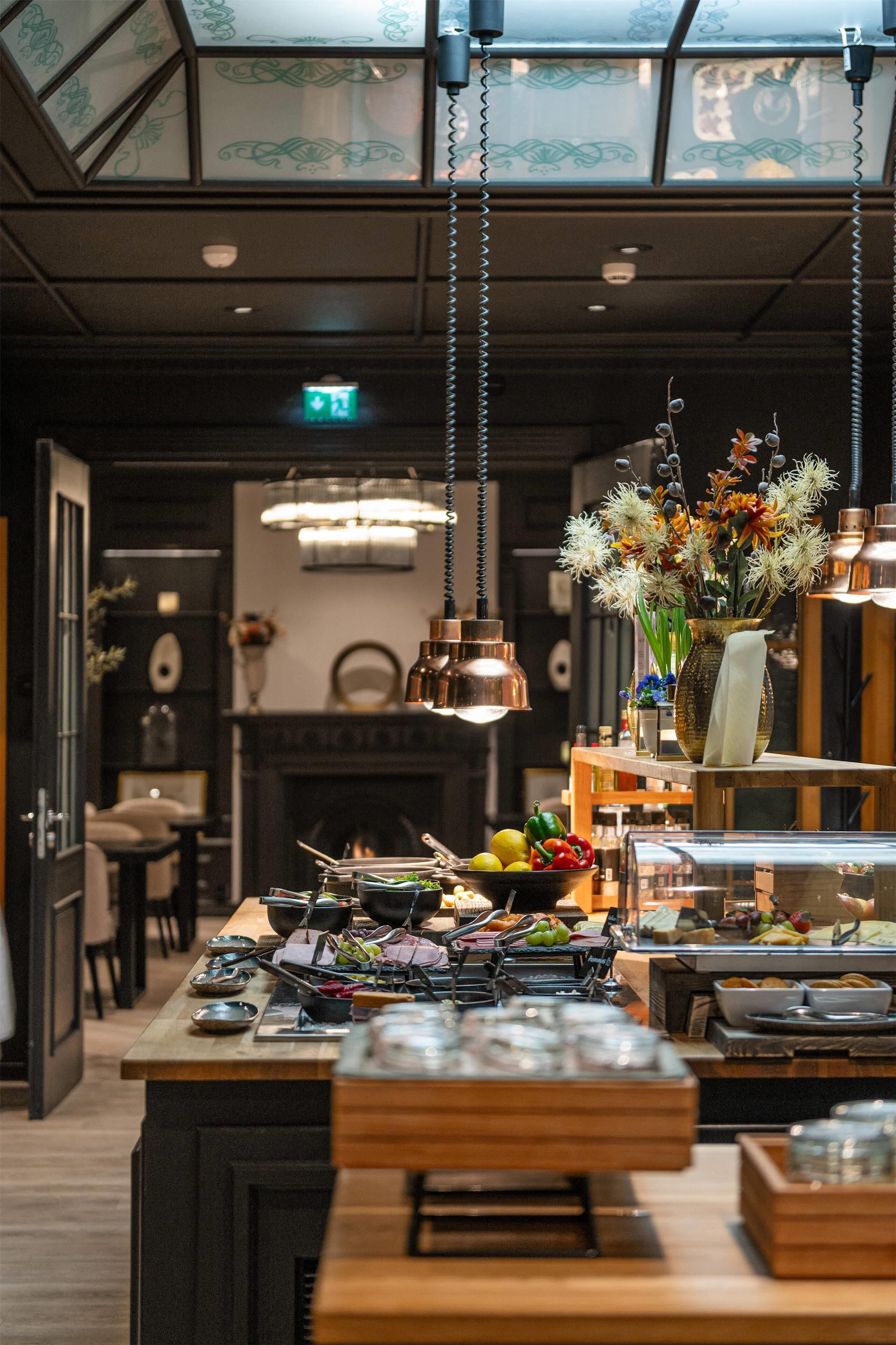 Un interior de restaurante con una barra de madera, luces colgantes y un florero con flores.