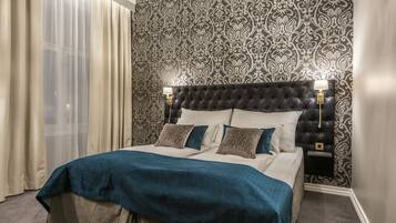 A neatly made bed with a blue bedspread and white linens, a black tufted headboard, and a nightstand with a lamp.