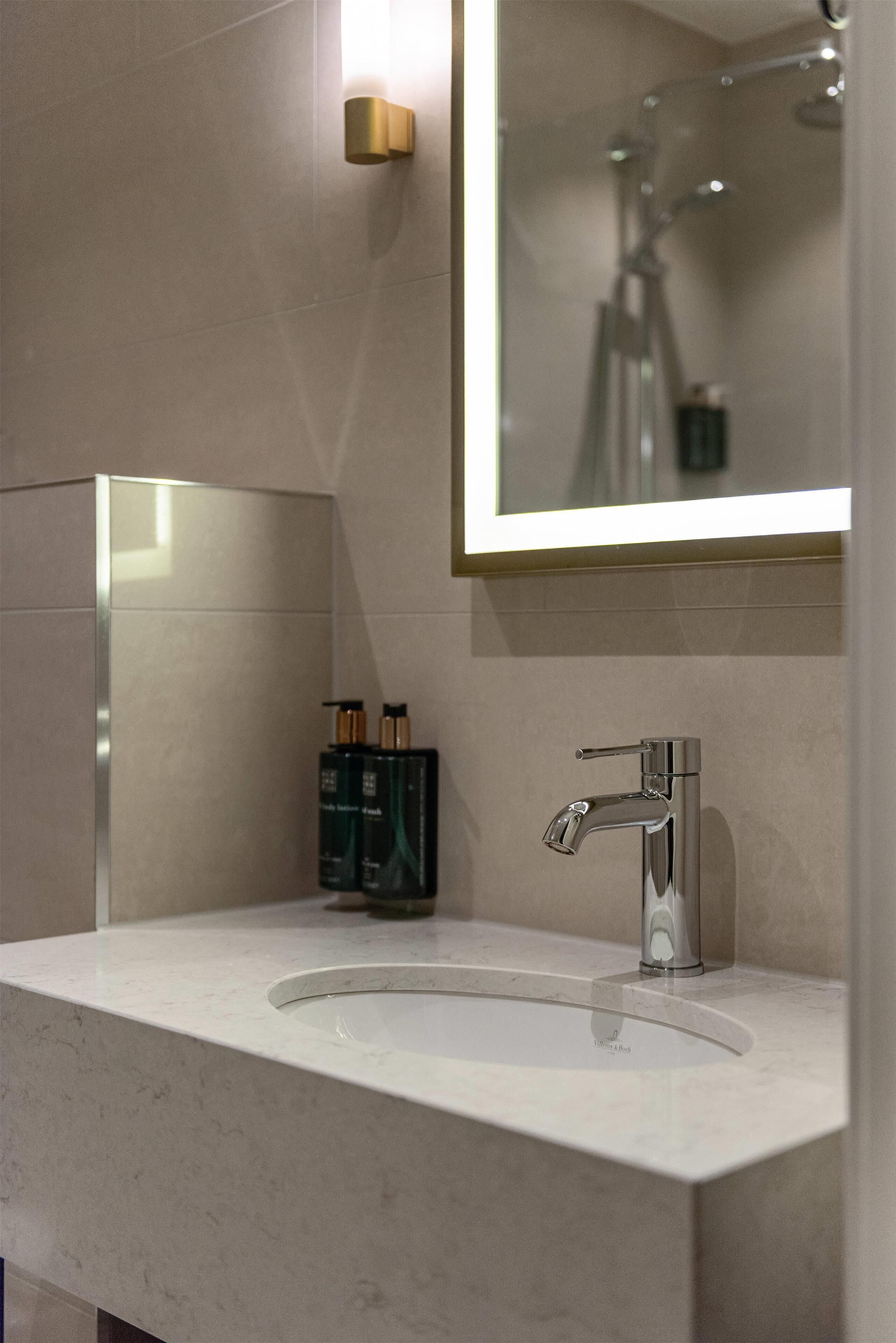 A bathroom with a large mirror, a modern sink, and a shower.