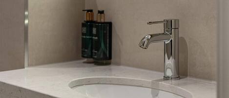 A bathroom with a large mirror, a modern sink, and a shower.