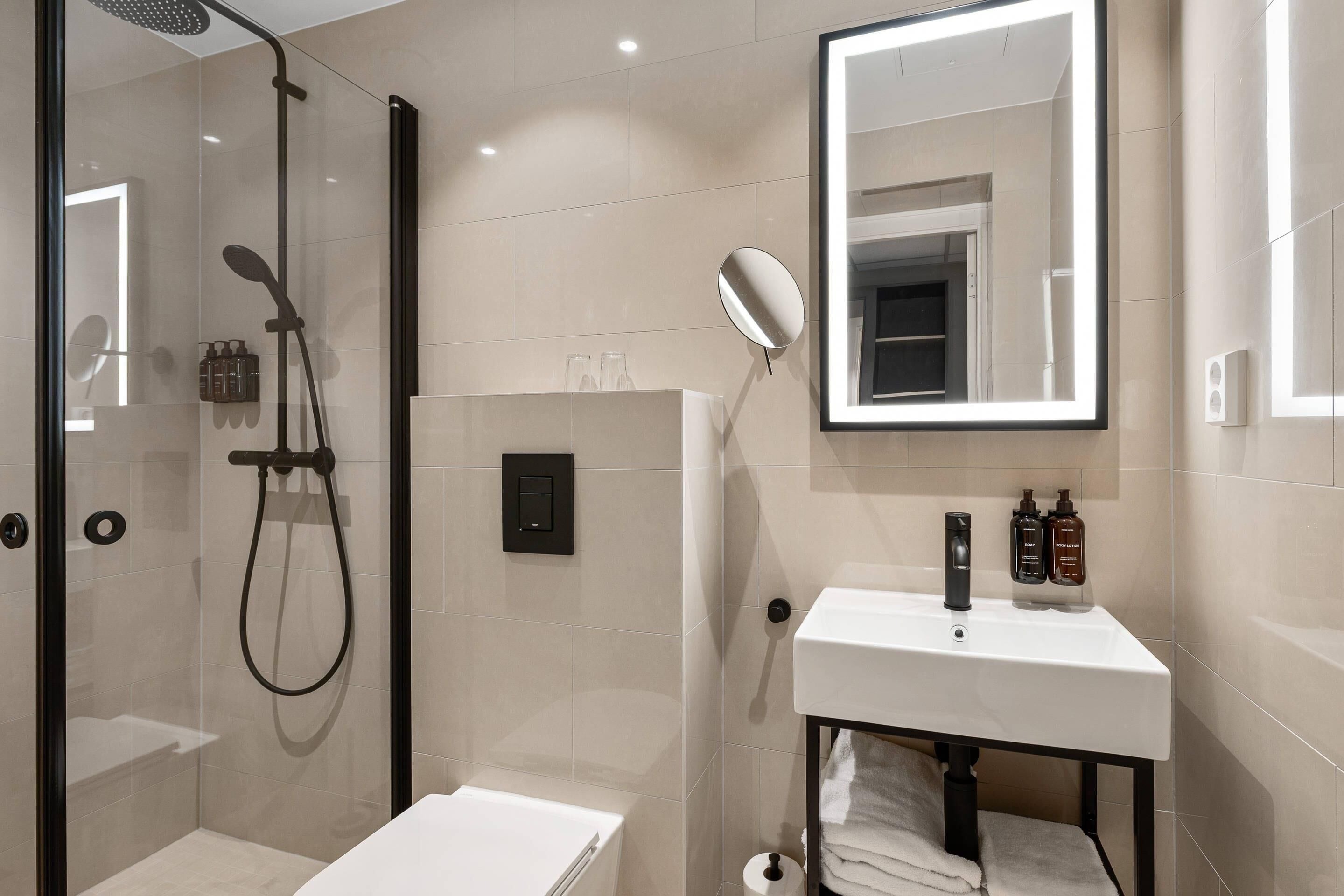 Une salle de bain moderne avec une douche à parois de verre, un lavabo blanc avec un miroir et des toilettes.