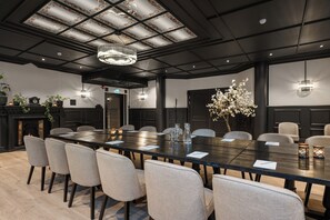 A conference room with a long table, chairs, a chandelier, and a fireplace. - Home Hotel Grand Gjovik (Gjovik)
