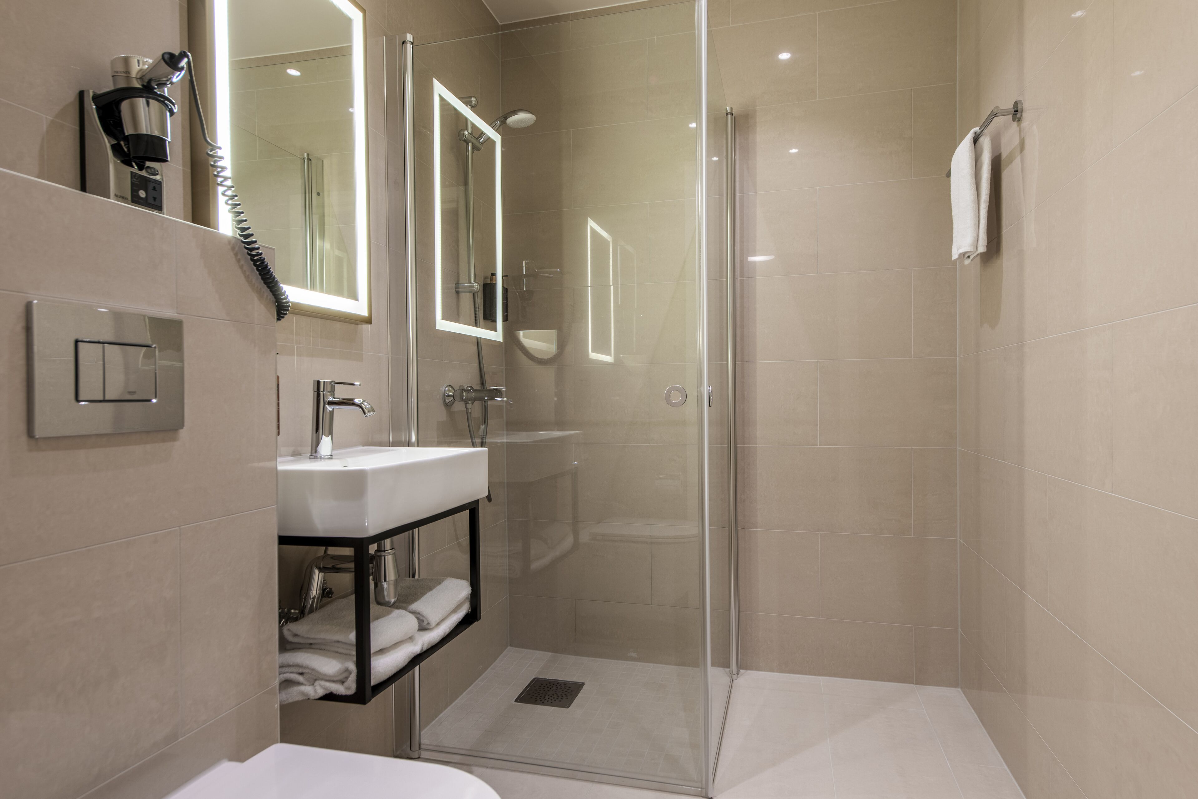 A modern bathroom with a glass-enclosed shower, a sink with a mirror, and a towel rack.