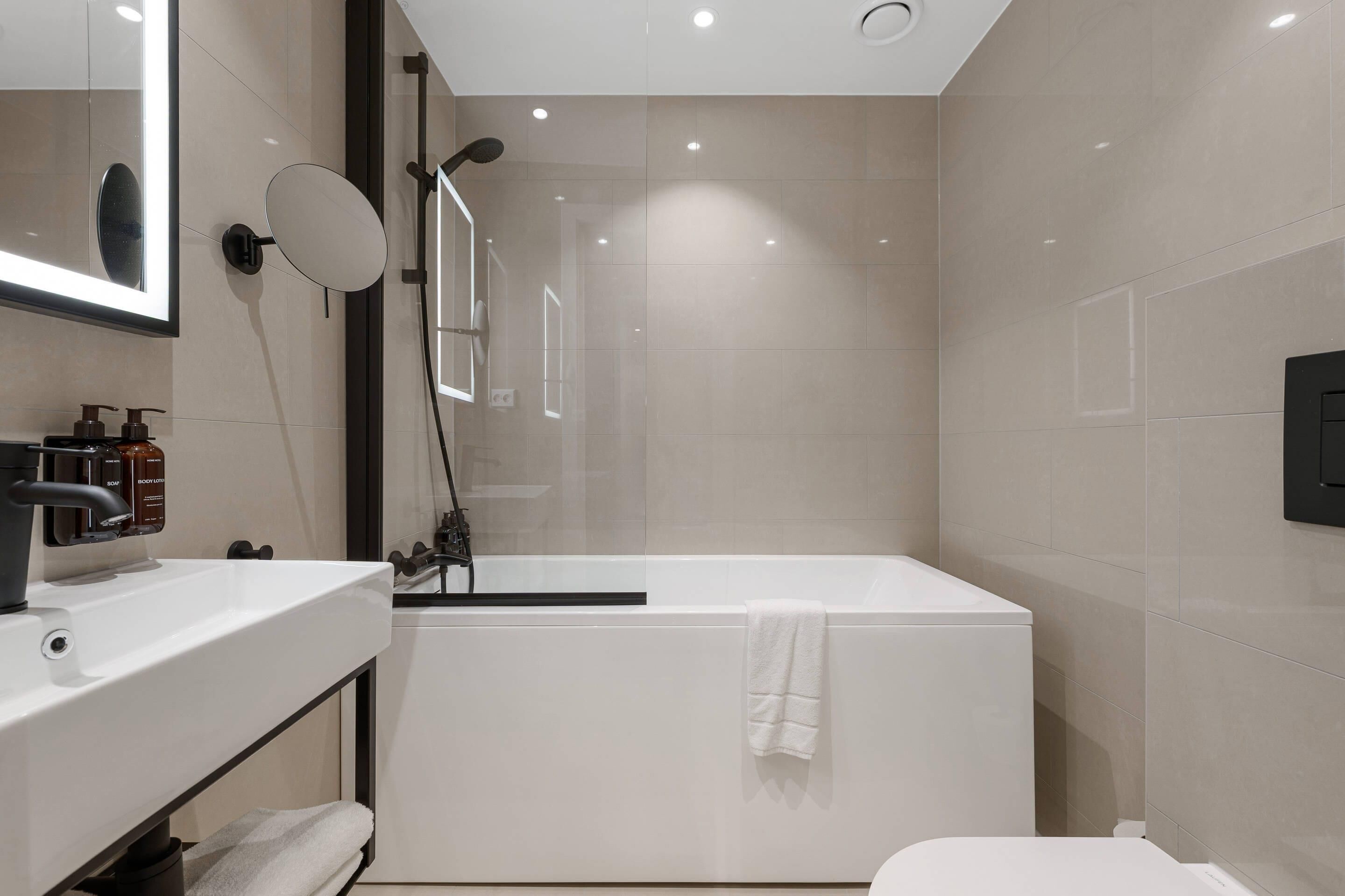 A modern bathroom with a white sink, mirror, and shower.