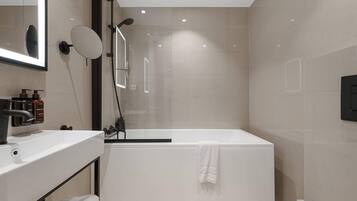Un baño moderno con lavamanos, espejo y ducha blancos.