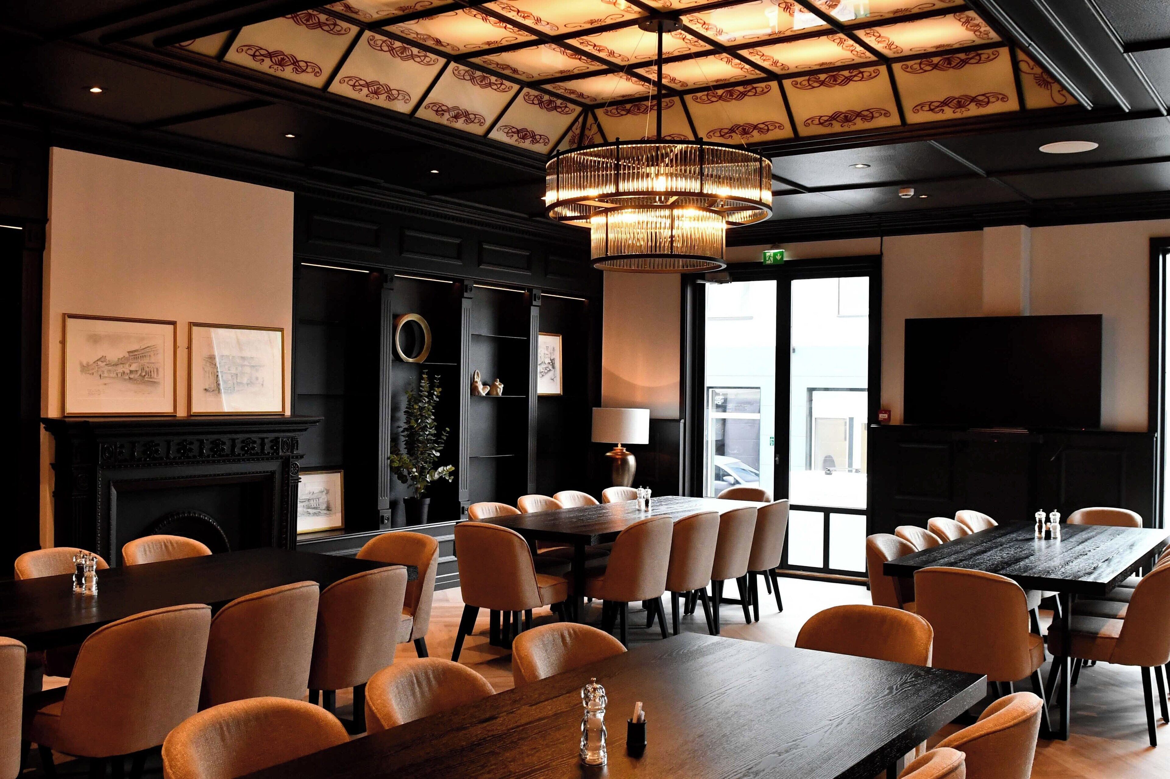 A conference room with a large table, multiple chairs, a fireplace, and a ceiling with a patterned design.