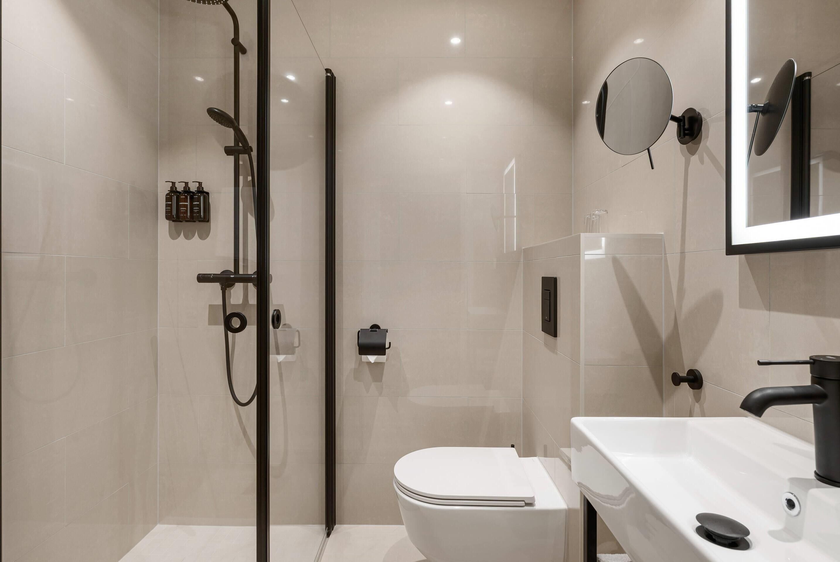 Un bagno moderno con cabina doccia in vetro, un water bianco e un lavandino con specchio.