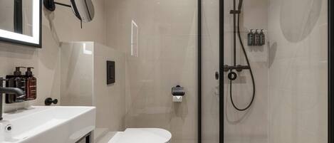 Un baño moderno con inodoro, lavamanos, espejo y ducha.