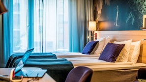 Una habitación de hotel con una cama, un escritorio con una computadora portátil y una silla.