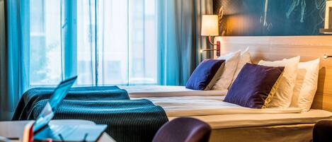 A hotel room with a bed, a desk with a laptop, and a chair.