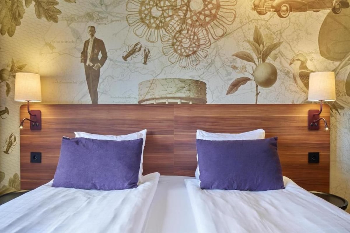 Ein Doppelbett mit zwei violetten Kissen und einem Holz-Kopfteil.