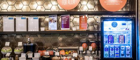 A breakfast buffet area with various food items and a refrigerated drink dispenser.