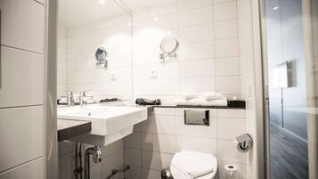 A modern bathroom with a white sink, mirror, and toilet.