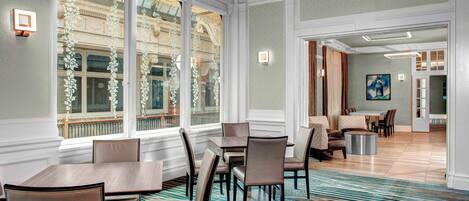 A dining area with a large table and chairs, a patterned carpet, and large windows with decorative glass panels.