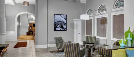 A spacious living area with a modern design, featuring a large window with stained glass, a chandelier, and a contemporary seating arrangement.