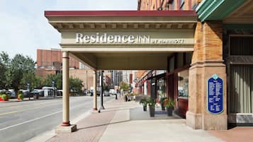 A hotel entrance with a covered walkway, a sign reading "Residence Inn by Marriott," and a plaque indicating the hotel is part of the Marriott brand.