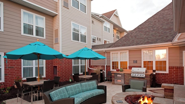 A patio area with a fire pit, outdoor furniture, and a grill.