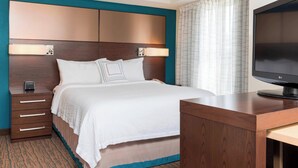 A hotel room with a bed, a desk, a television, and a nightstand.