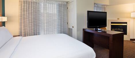 Una habitación de hotel con una cama grande, un televisor de pantalla plana, un escritorio y una chimenea.