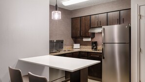 A modern kitchen with dark wooden cabinets, stainless steel appliances, and a white countertop. - Residence Inn by Marriott Boulder Broomfield (Louisville)