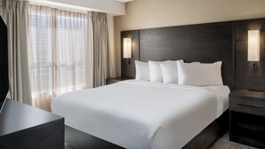 A modern hotel room with a large bed, a bedside table, a lamp, and a view of the city through sheer curtains. - Residence Inn by Marriott Boulder Broomfield (Louisville)