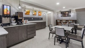 A modern kitchen with a large island, built-in appliances, and a dining area with tables and chairs.