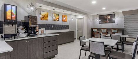 A modern kitchen with a large island, built-in appliances, and a dining area with tables and chairs.