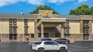 A Comfort Inn with a stone facade, multiple parking spaces, and a clear blue sky.