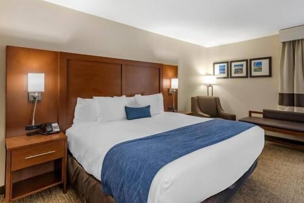 Une chambre d’hôtel avec un grand lit, des tables de chevet, un bureau et une chaise.