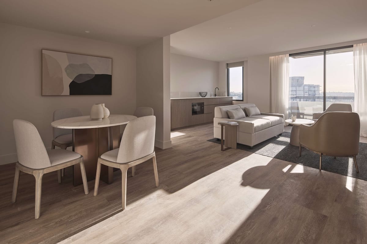 A modern living room with a dining area, a sofa set, and a large window offering a city view.