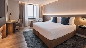 A modern hotel room with a large bed, a desk, a chair, and a small table. - Rydges North Sydney (North Sydney)