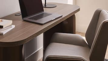 A modern office desk with a laptop, a lamp, and a chair.