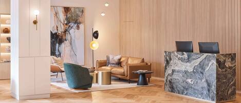 Un vestíbulo moderno con mostrador de recepción de madera, sofás de cuero y una obra de arte de mármol.