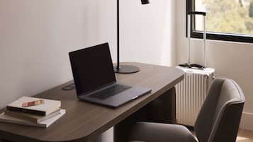 A laptop on a wooden desk with a radiator and a window in the background.