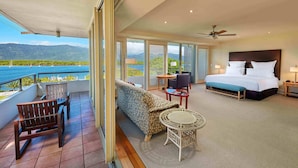 Een hotelkamer met balkon, een bed, een bank, een tafeltje en een stoel.