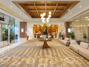 A hotel lobby with a reception desk, seating area, and a patterned carpet.